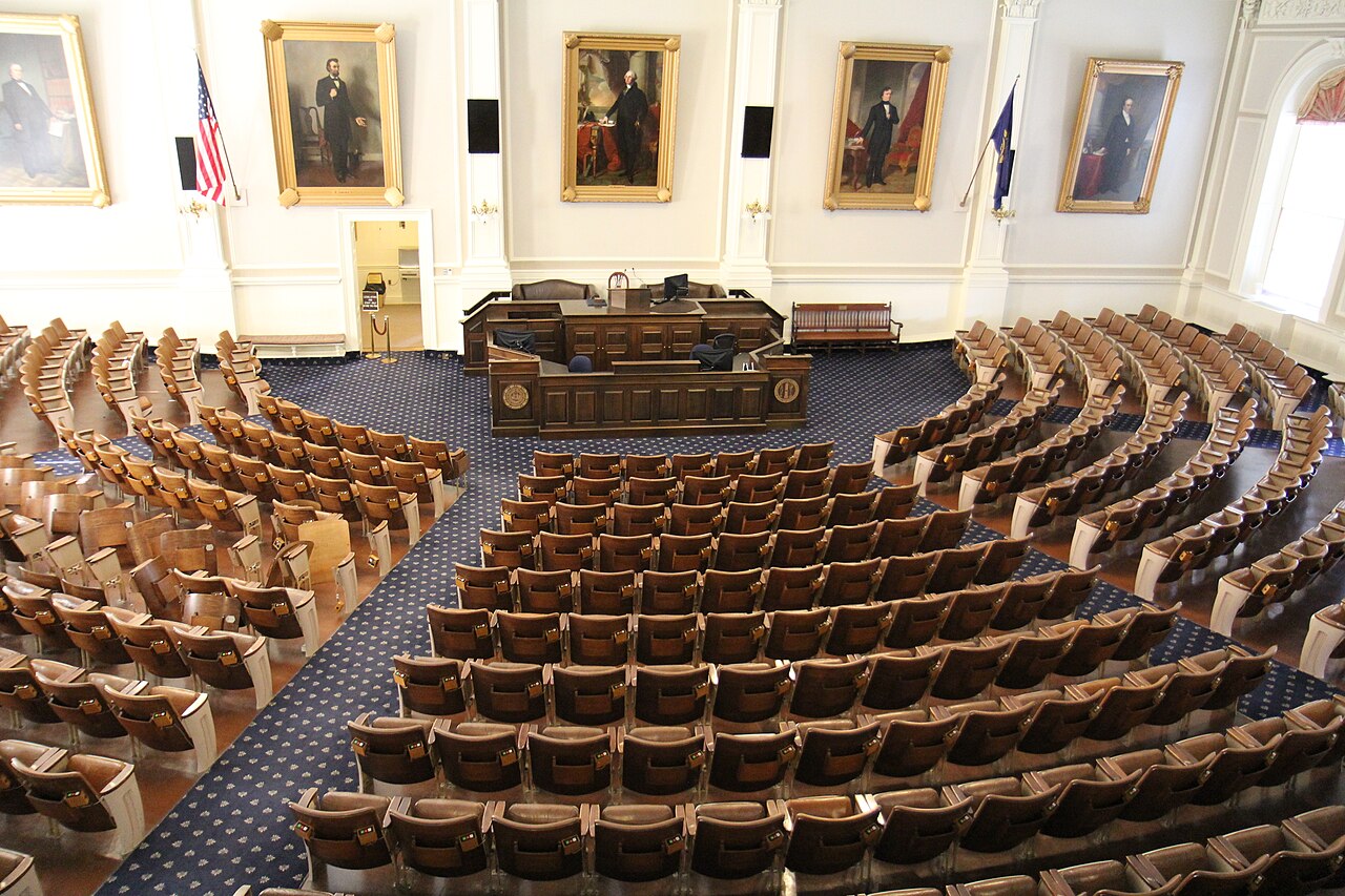 Rows of seats and the rostrum in the New Hampshire House of Representatives chamber, viewed from the balcony.