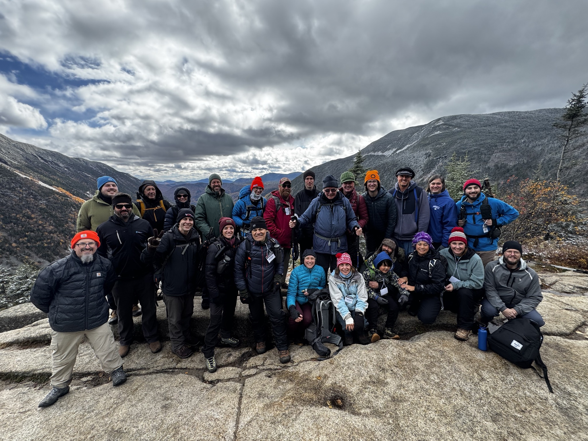 Granite Freedom Trek participants at the summit of Mount Willard, with autumn colors and snow-dusted mountains behind them.